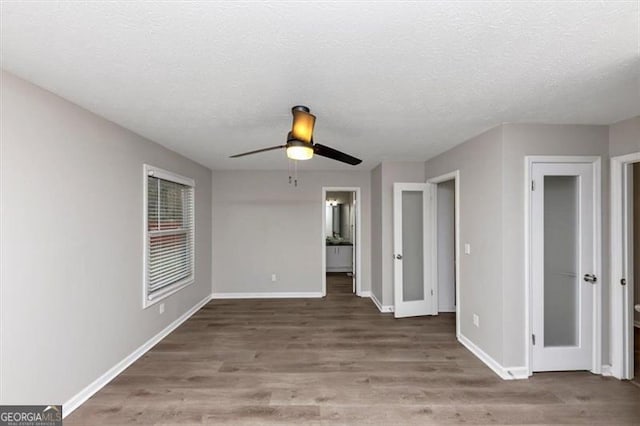 unfurnished room with ceiling fan, wood-type flooring, and a textured ceiling