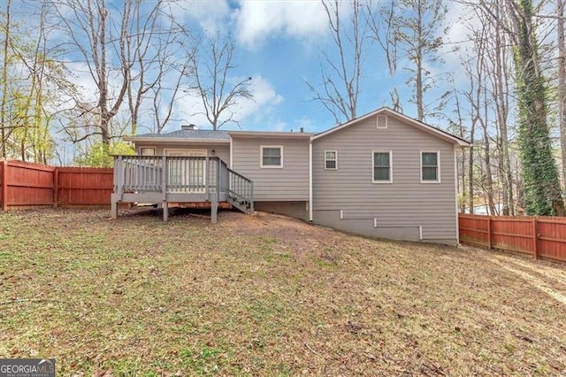 back of house featuring a deck and a lawn