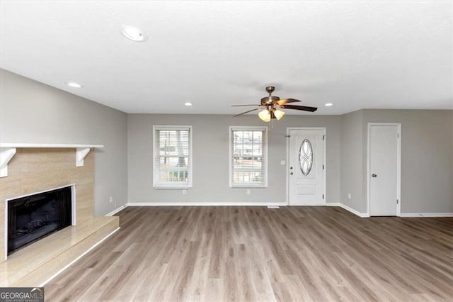 interior space featuring ceiling fan, a fireplace, and light hardwood / wood-style floors