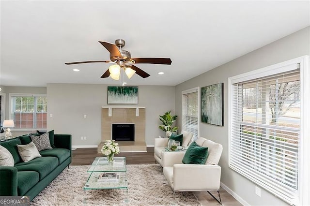 living room featuring a tile fireplace, hardwood / wood-style floors, and ceiling fan