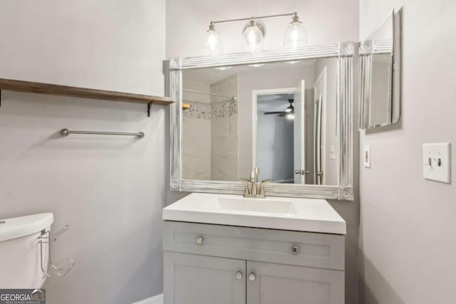 bathroom with vanity, tiled shower, and toilet