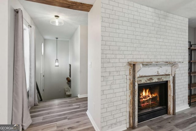 unfurnished living room with hardwood / wood-style flooring and a brick fireplace