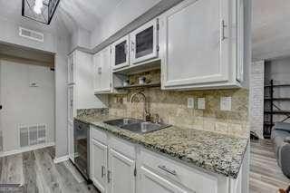 kitchen with tasteful backsplash, white cabinetry, light stone counters, and light hardwood / wood-style floors