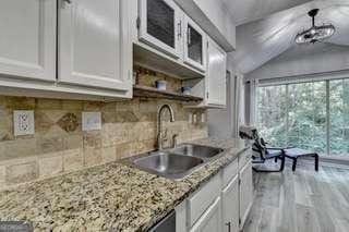 kitchen featuring sink, white cabinets, backsplash, light stone counters, and light hardwood / wood-style flooring