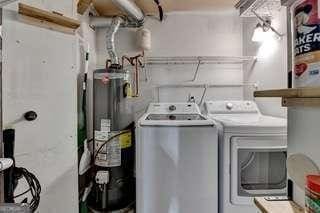 clothes washing area with washing machine and dryer and water heater