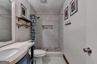 bathroom featuring a shower with curtain, vanity, and toilet