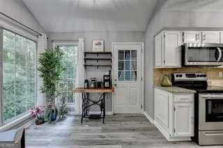 kitchen with white cabinetry, lofted ceiling, stainless steel appliances, and light hardwood / wood-style flooring