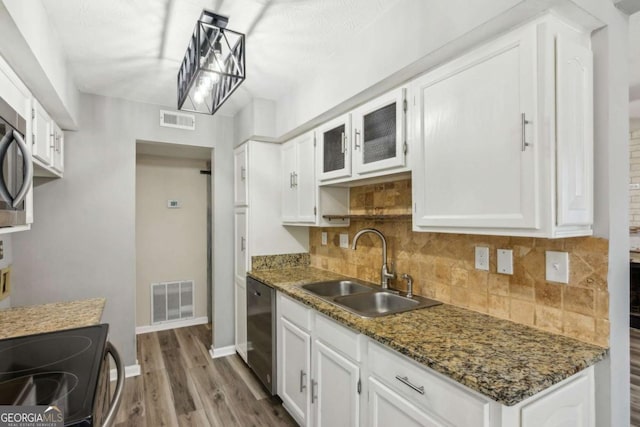 kitchen featuring dark stone countertops, sink, stainless steel dishwasher, and white cabinets