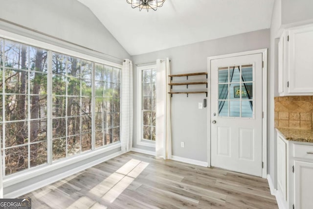 unfurnished dining area with lofted ceiling and light hardwood / wood-style flooring