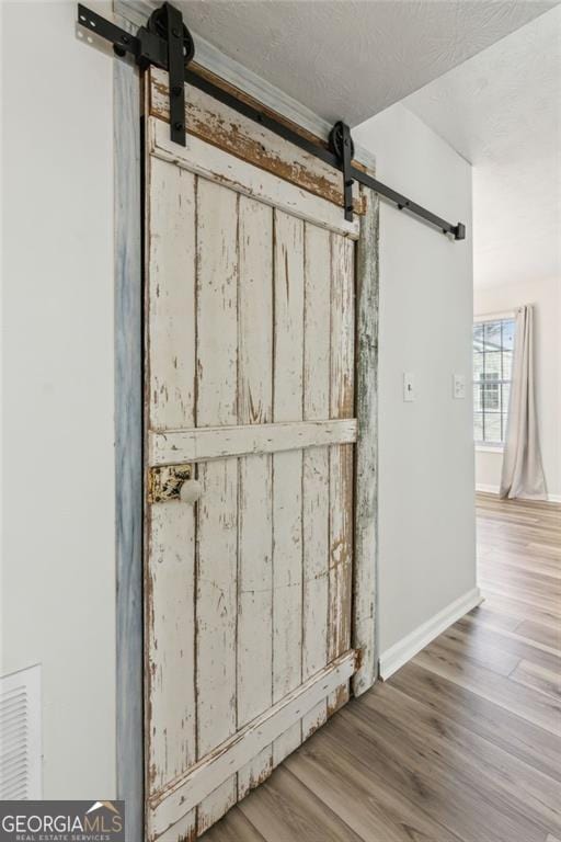 room details with wood-type flooring, a barn door, and a textured ceiling