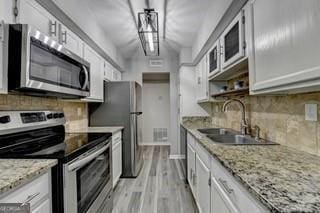 kitchen featuring white cabinetry, sink, light stone countertops, and appliances with stainless steel finishes