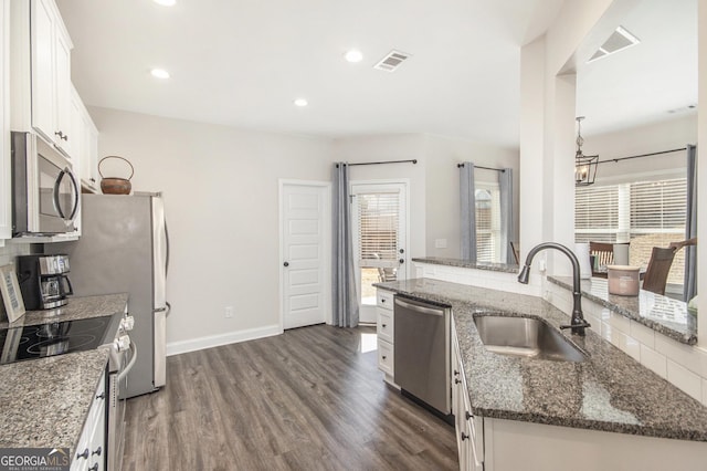 kitchen featuring sink, white cabinetry, dark stone countertops, stainless steel appliances, and dark hardwood / wood-style flooring