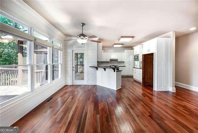 kitchen featuring ceiling fan, white cabinetry, dark hardwood / wood-style floors, stainless steel microwave, and kitchen peninsula