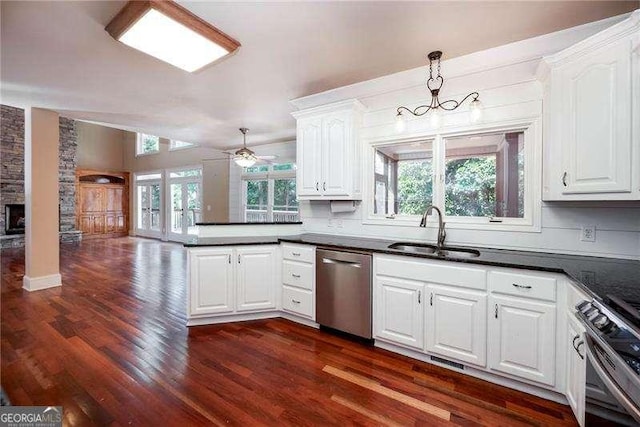 kitchen featuring appliances with stainless steel finishes, decorative light fixtures, sink, white cabinets, and dark hardwood / wood-style flooring