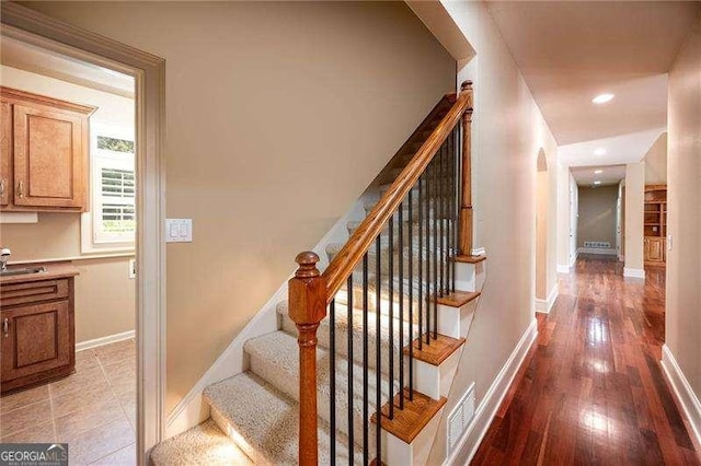 stairs featuring sink and hardwood / wood-style floors