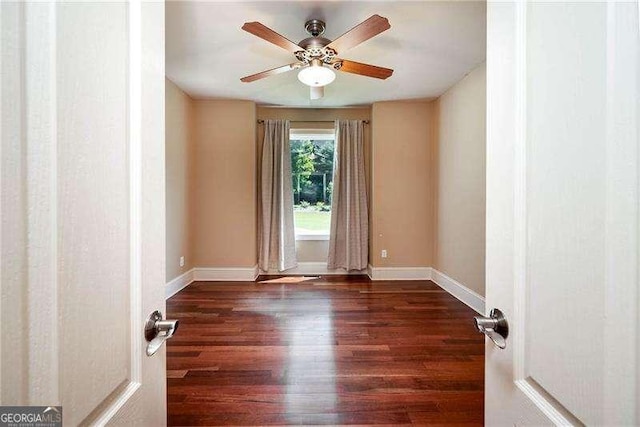 empty room with ceiling fan and dark hardwood / wood-style flooring