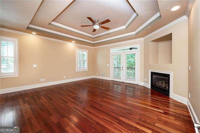 unfurnished living room featuring crown molding, ceiling fan, a tray ceiling, and dark hardwood / wood-style flooring