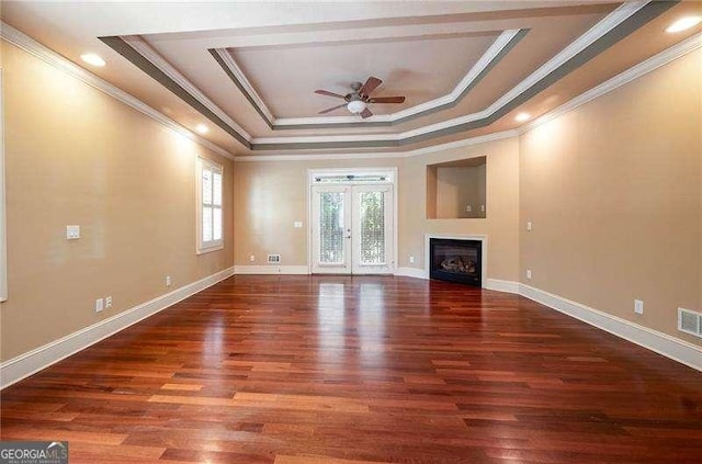 unfurnished living room with dark hardwood / wood-style floors, ceiling fan, a raised ceiling, crown molding, and french doors