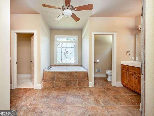 bathroom featuring ceiling fan, vanity, toilet, and tiled tub