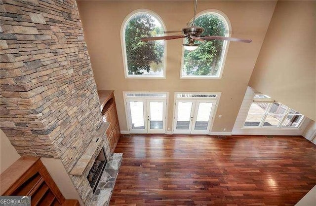 unfurnished living room with a towering ceiling, dark hardwood / wood-style floors, ceiling fan, and french doors