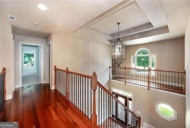 corridor featuring an inviting chandelier, dark hardwood / wood-style flooring, and a raised ceiling