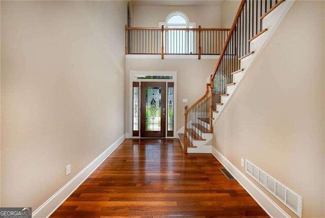 entryway featuring a towering ceiling, dark hardwood / wood-style flooring, and a wealth of natural light