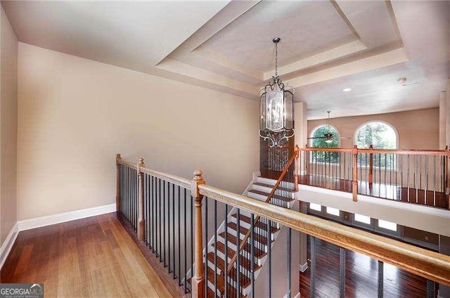 hall featuring a tray ceiling, a chandelier, and hardwood / wood-style flooring