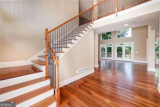 stairs with hardwood / wood-style floors and a high ceiling