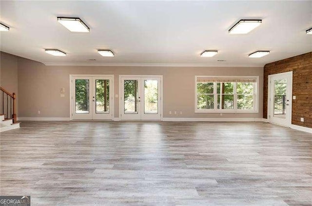 unfurnished room featuring ornamental molding, plenty of natural light, light hardwood / wood-style floors, and french doors