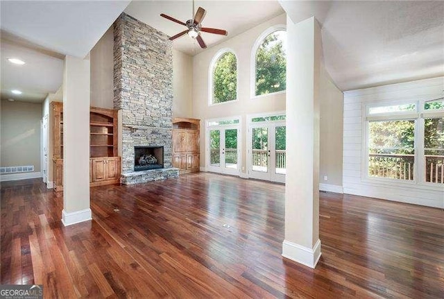 unfurnished living room featuring a towering ceiling, a fireplace, dark hardwood / wood-style floors, and ceiling fan