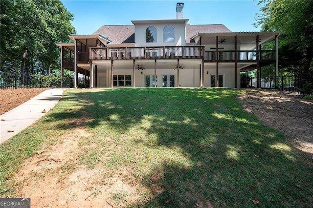 back of property featuring ceiling fan, a yard, and a deck