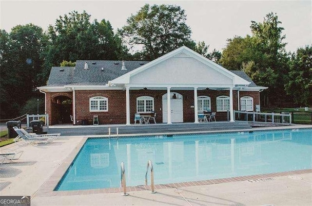 view of swimming pool featuring a patio and an outbuilding