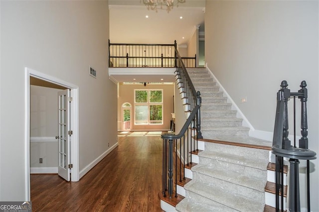 staircase featuring wood-type flooring, a chandelier, and a high ceiling