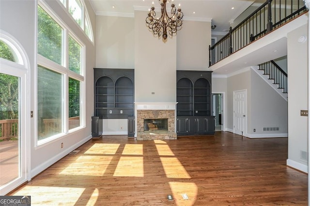 unfurnished living room with crown molding, a stone fireplace, and hardwood / wood-style floors