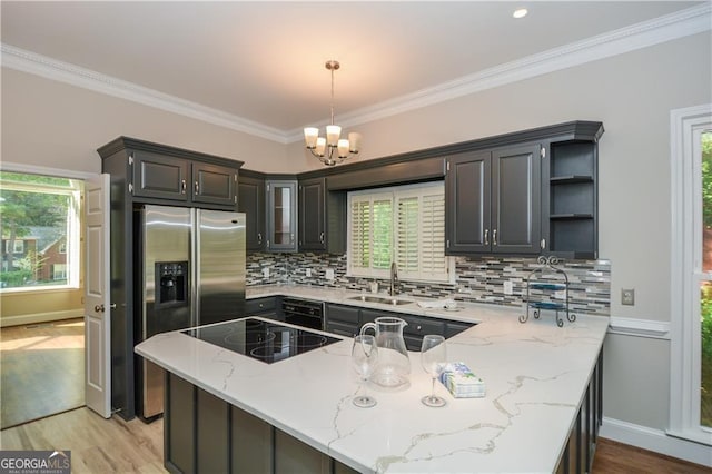 kitchen with sink, light stone counters, hanging light fixtures, kitchen peninsula, and black electric stovetop