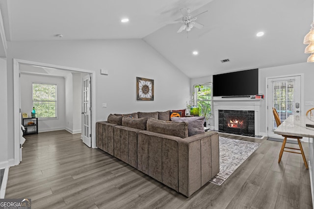 living room with vaulted ceiling, ceiling fan, a fireplace, and light wood-type flooring