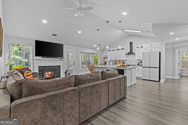 living room with a fireplace, light hardwood / wood-style flooring, sink, and plenty of natural light