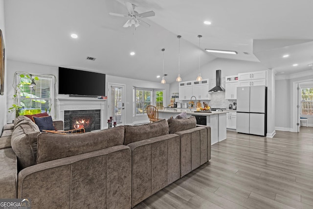 living room with a tiled fireplace, sink, a wealth of natural light, and light hardwood / wood-style floors