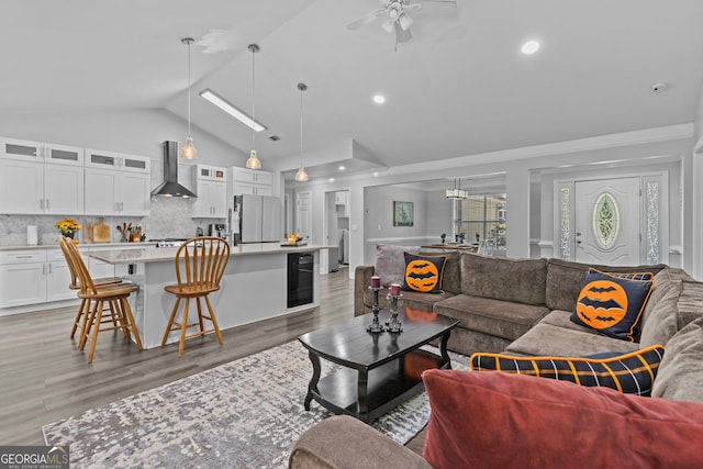 living room featuring ceiling fan, high vaulted ceiling, beverage cooler, and light wood-type flooring