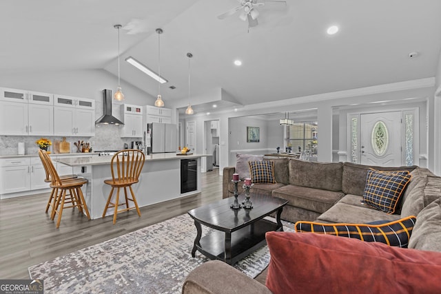 living room with high vaulted ceiling, beverage cooler, ceiling fan, and light hardwood / wood-style flooring