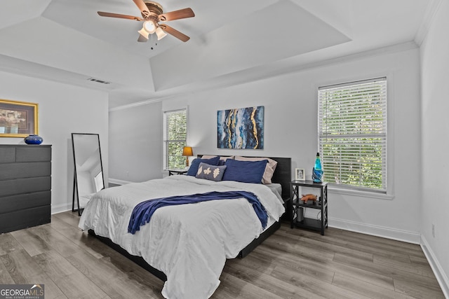 bedroom featuring crown molding, a tray ceiling, ceiling fan, and hardwood / wood-style flooring