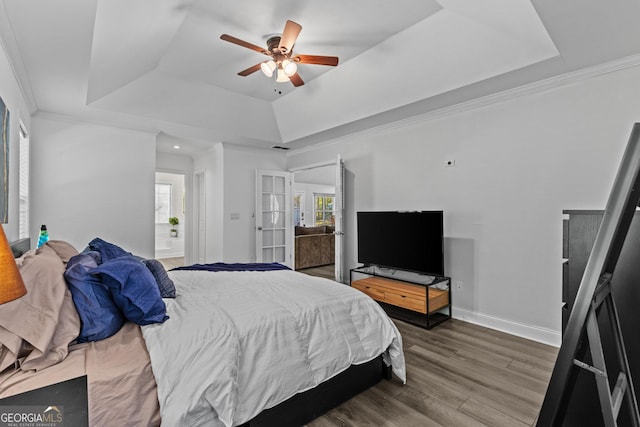 bedroom with hardwood / wood-style flooring, ornamental molding, and a raised ceiling