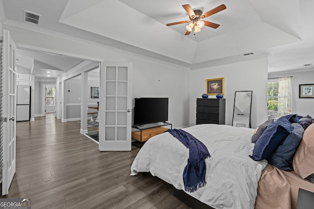 bedroom featuring french doors, hardwood / wood-style flooring, a raised ceiling, and white refrigerator