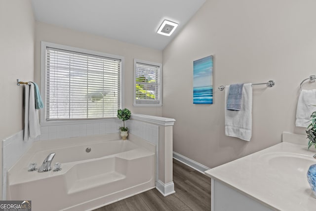 bathroom featuring hardwood / wood-style floors, vaulted ceiling, a bath, and vanity