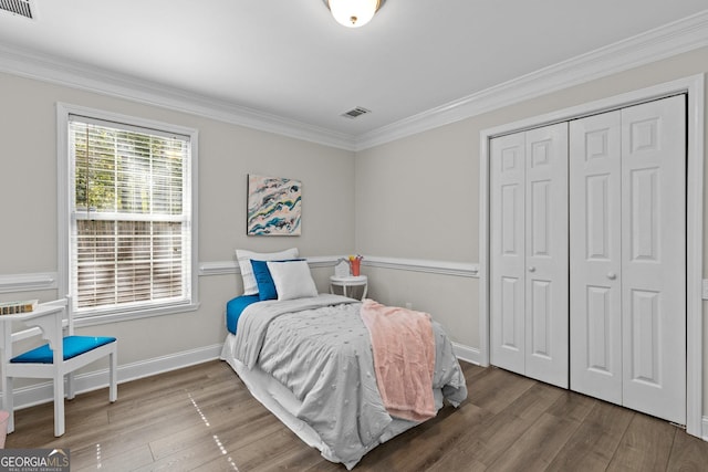 bedroom with hardwood / wood-style floors, ornamental molding, and a closet