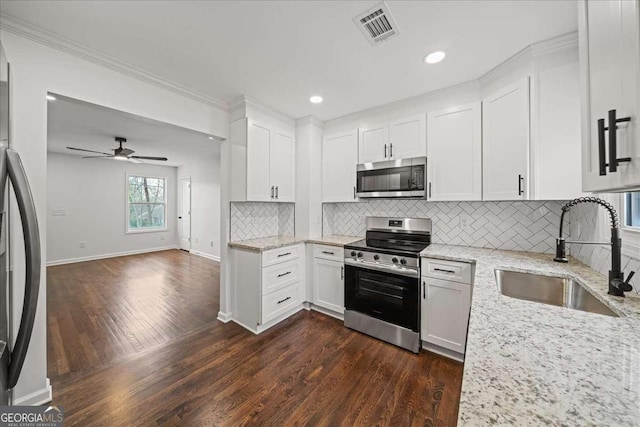 kitchen with sink, appliances with stainless steel finishes, white cabinets, light stone countertops, and backsplash