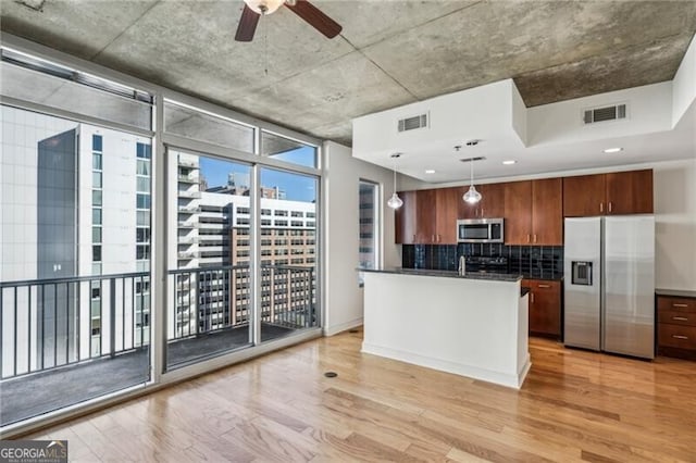 kitchen with stainless steel appliances, hanging light fixtures, light wood-type flooring, and expansive windows