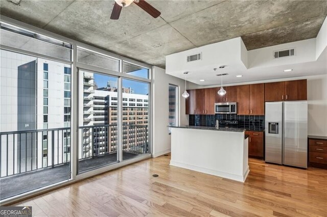44 Peachtree Pl NW Unit 1828, Atlanta, GA 30309 - kitchen with stainless steel appliances, light wood finished floors, dark countertops, backsplash, and hanging light fixtures