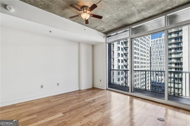 unfurnished room with a wall of windows, light hardwood / wood-style floors, and ceiling fan