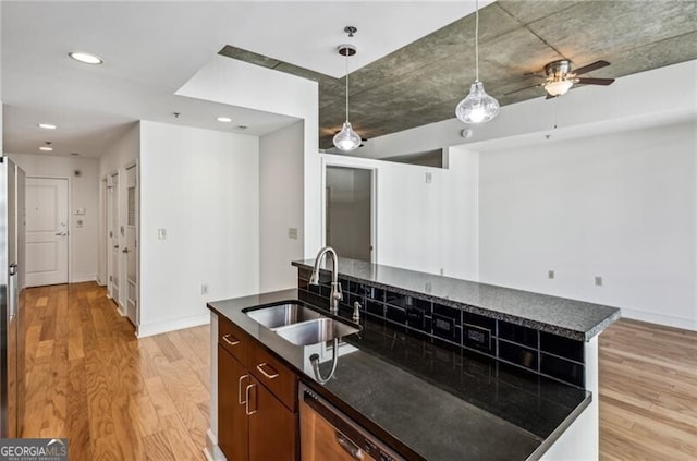 kitchen with pendant lighting, sink, a center island, and light wood-type flooring